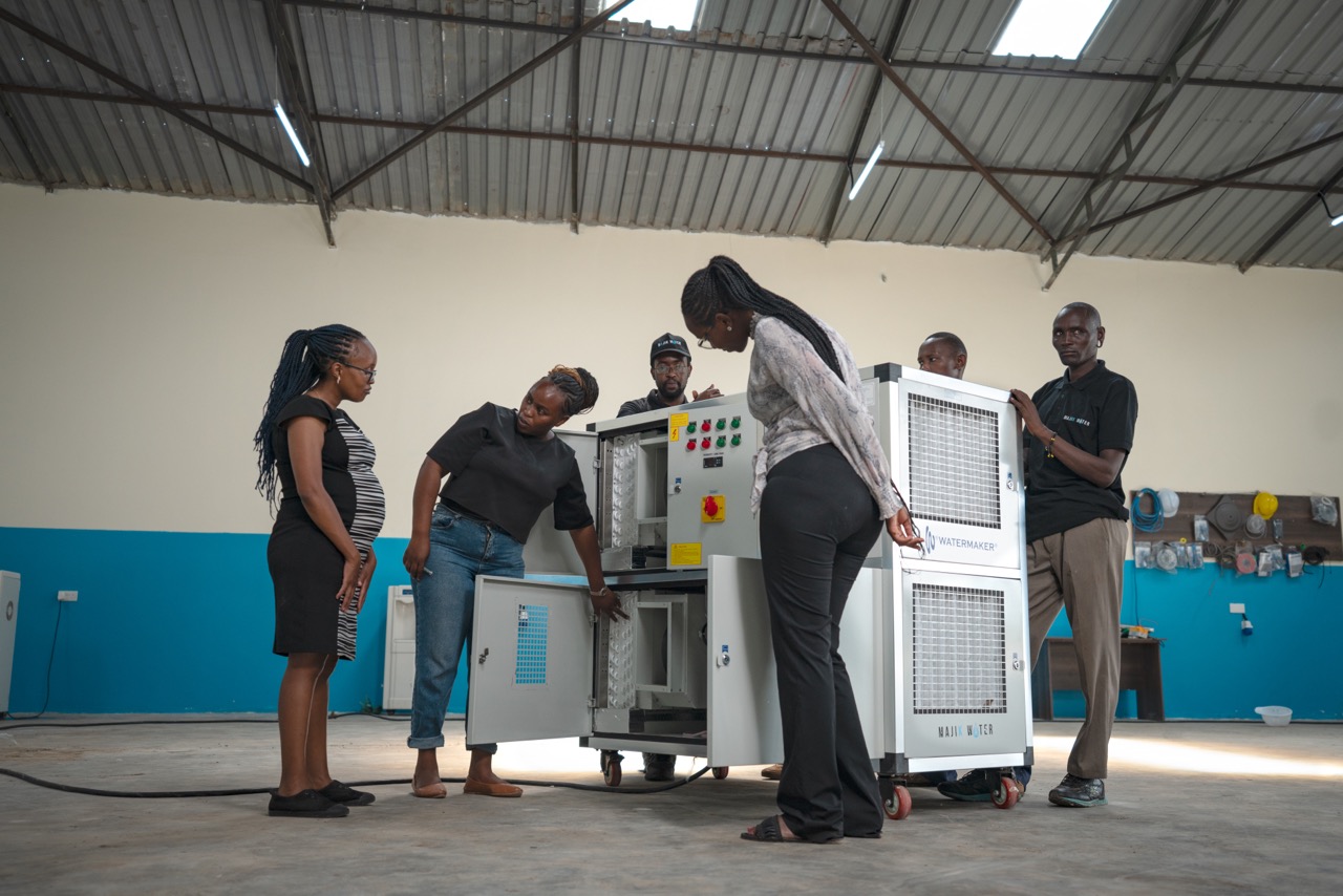2023 Rolex Awards for Enterprise Laureate Beth Koigi explaining the technical details of an Atmospheric Water Generator to her team in a Majik Water warehouse. Majik Water installs these machines in arid and semi-arid regions where they extract clean, mineralised water from thin air.