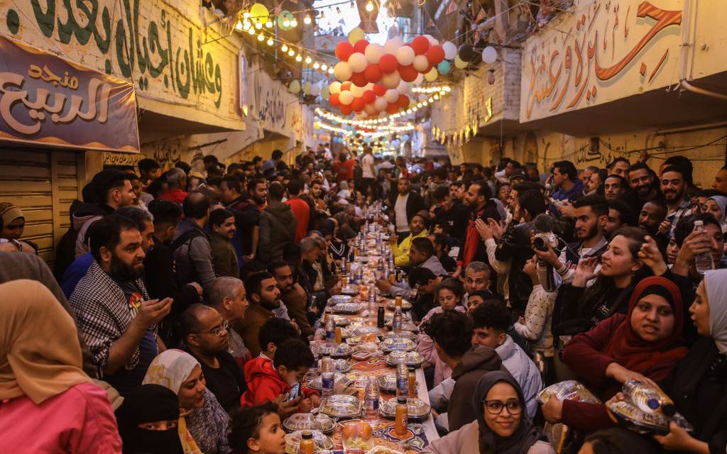Los egipcios rompen colectivamente su iftar en las mesas colocadas en las calles durante el Ramadán en 2024.